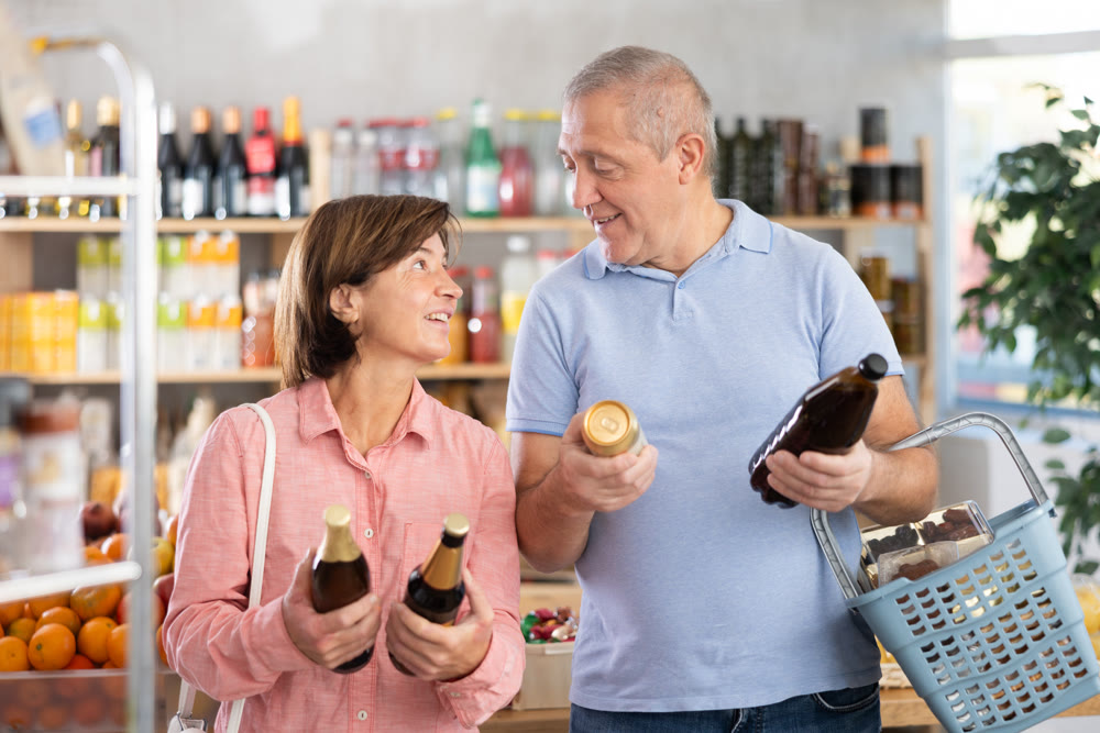 Elderly man and woman choose different beer together in grocery supermarket