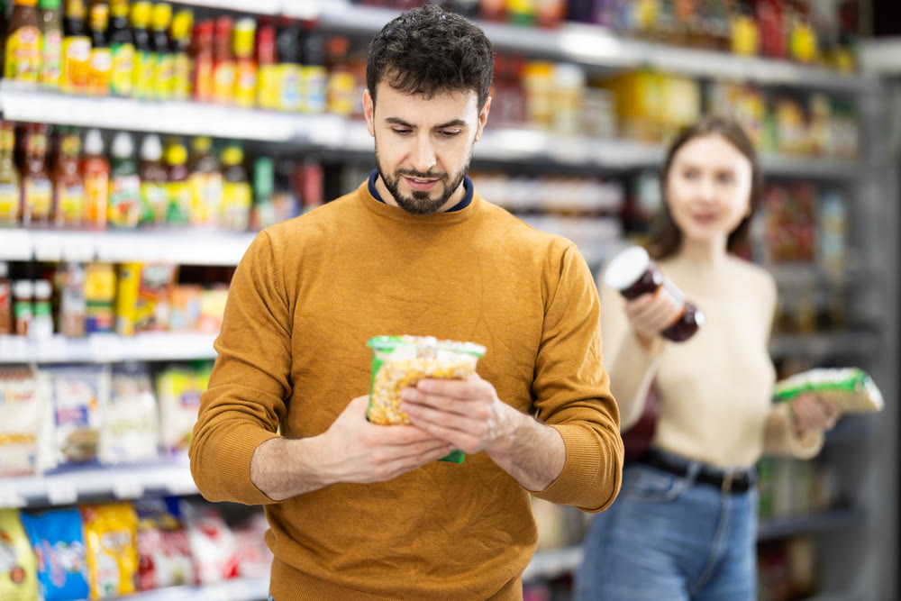 Young couple chooses beans and sauce at store