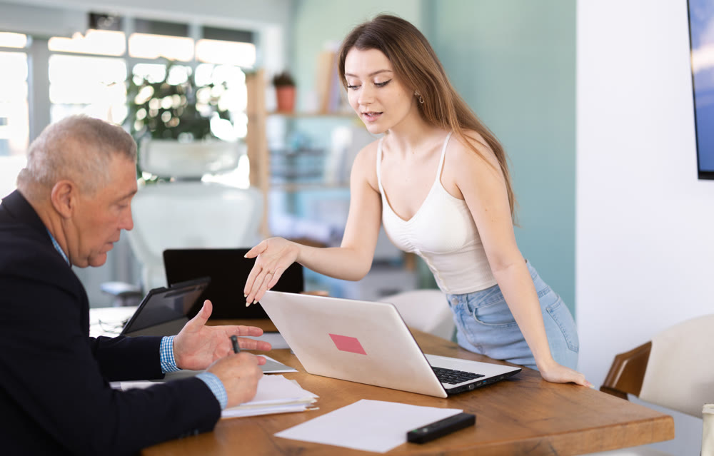 Young woman working in team with mature man, they sitting at table