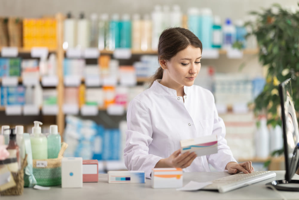 Female pharmacist updating stock inventory on pharmacy computer
