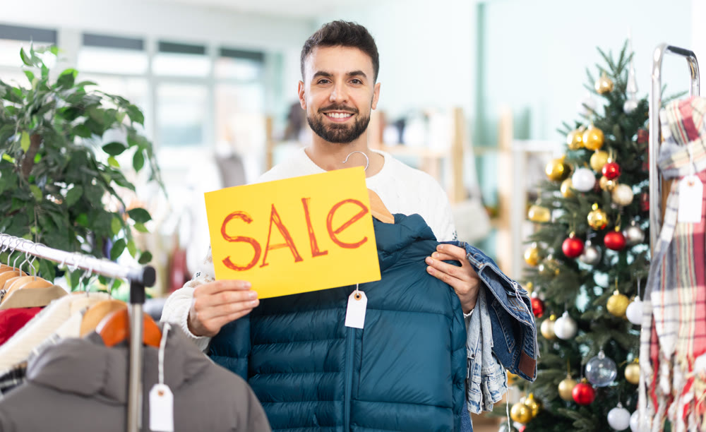 Young man presents sale sign in clothing store