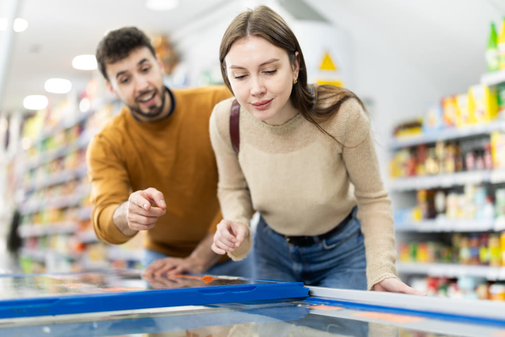 Young couple choosing frozen food in grocery store