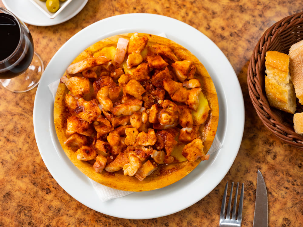 Chopped spicy boiled octopus tentacles with potato slices traditionally seasoned with aromatic paprika
