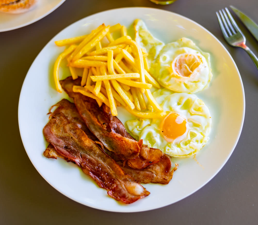 Homemade hearty breakfast - fried eggs with bacon and French fries
