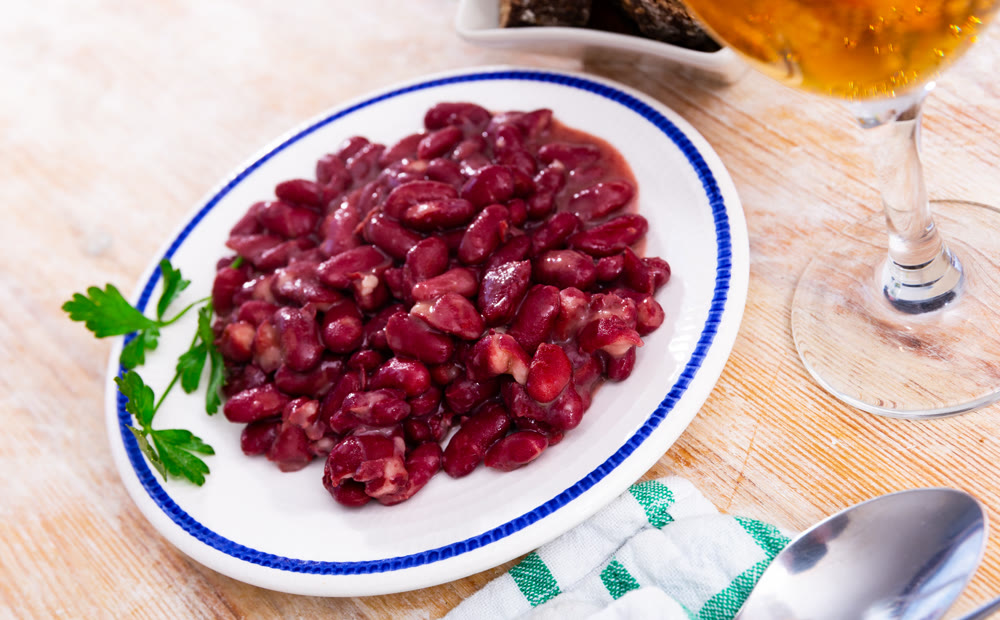 Plate contains light side dish of stewed vegetables - red kidney beans