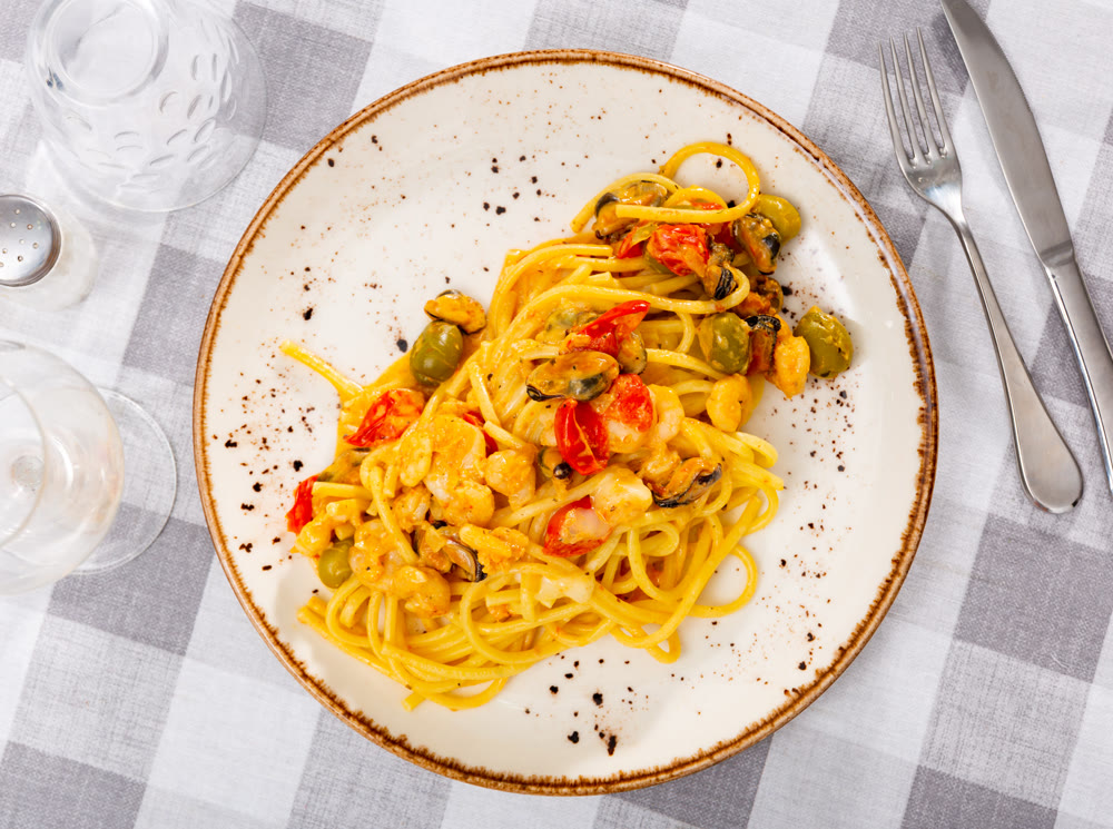 Pasta macaroni with seafood contains tiger prawns, shell mussels, spices and white sauce