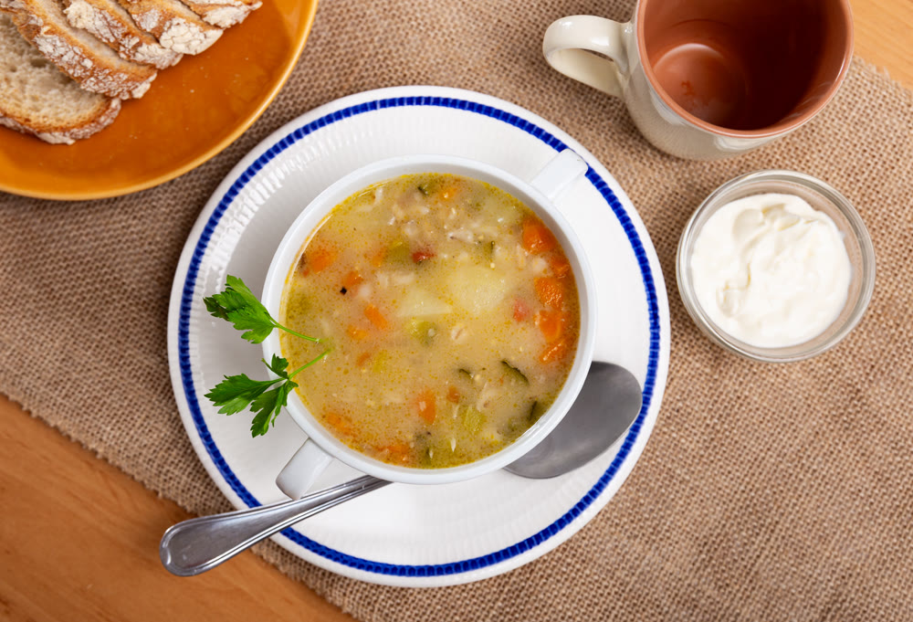 Popular dish of Russian cuisine is pickle soup with meat, cooked on basis of pickled cucumbers and pearl barley or rice, decorated with sprig of parsley