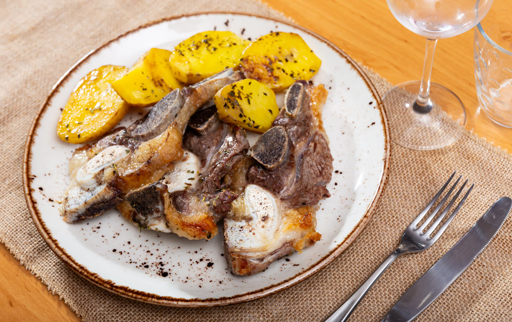 On white plate-grilled beef ribs garnished with fried potatoes