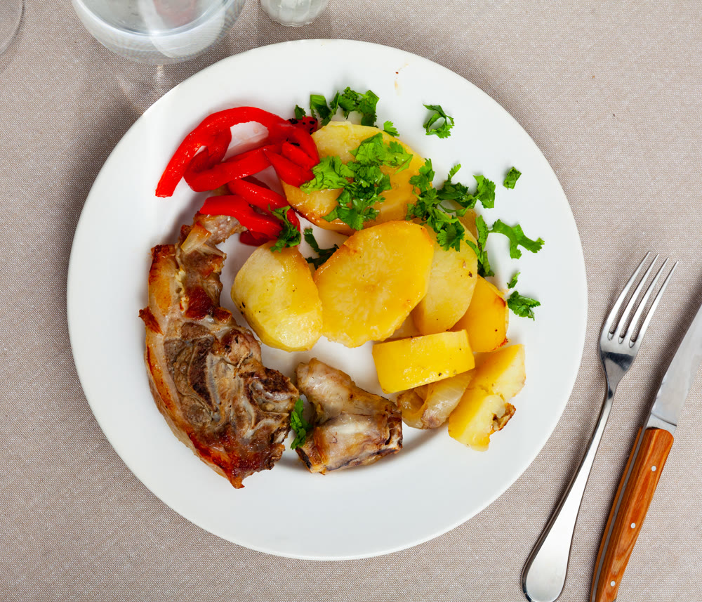 Side dish of baked lamb leg with potatoes and pepper