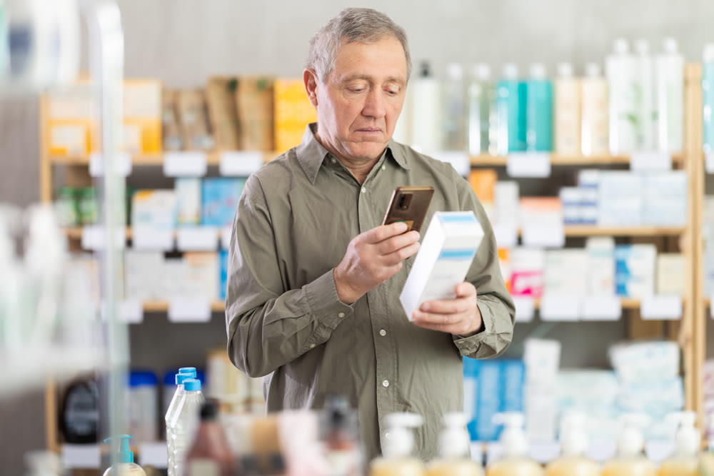 Senior man in pharmacy scans QR code on atopic cream