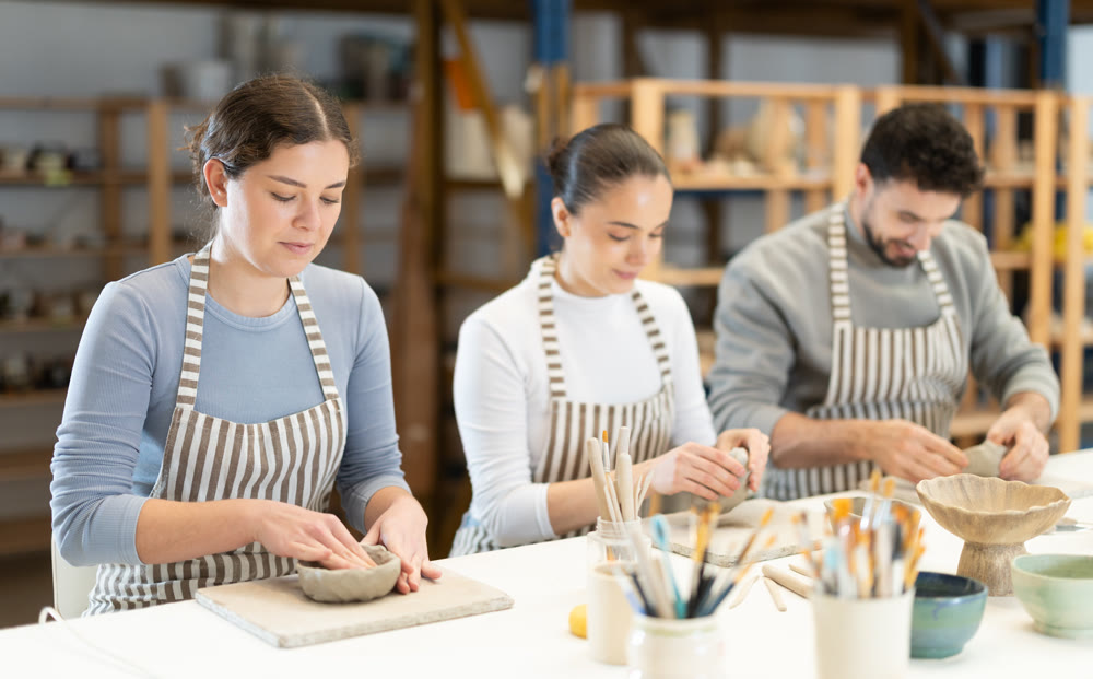 Three pottery workshop workers sculpt from clay, form final product