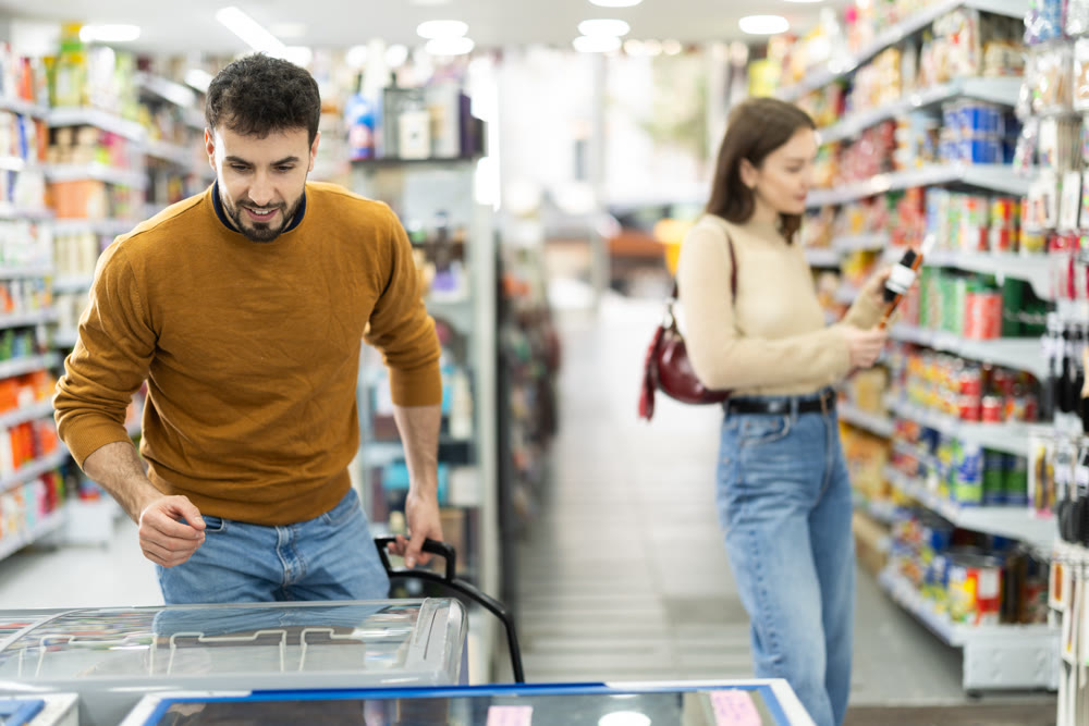Man choosing frozen food in supermarket. Man purchasing goods in store