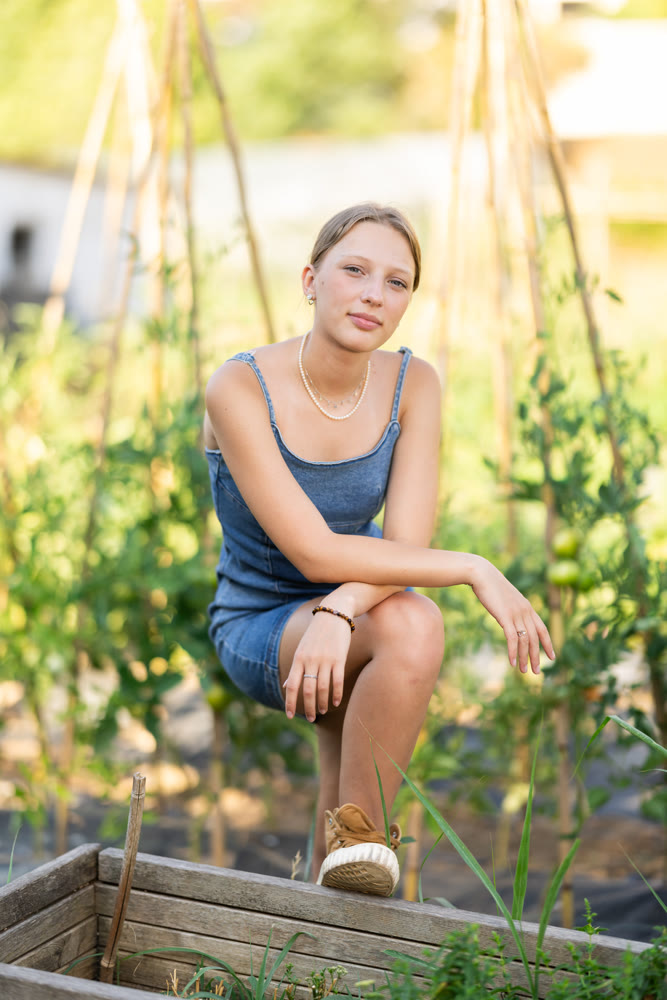 Rural dweller girl in straw hat with watering can against background of vegetable beds