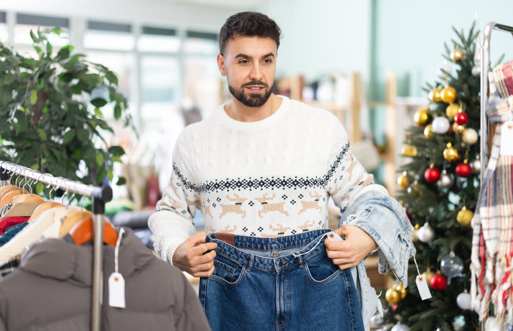 Young man choosing jeans in clothing store