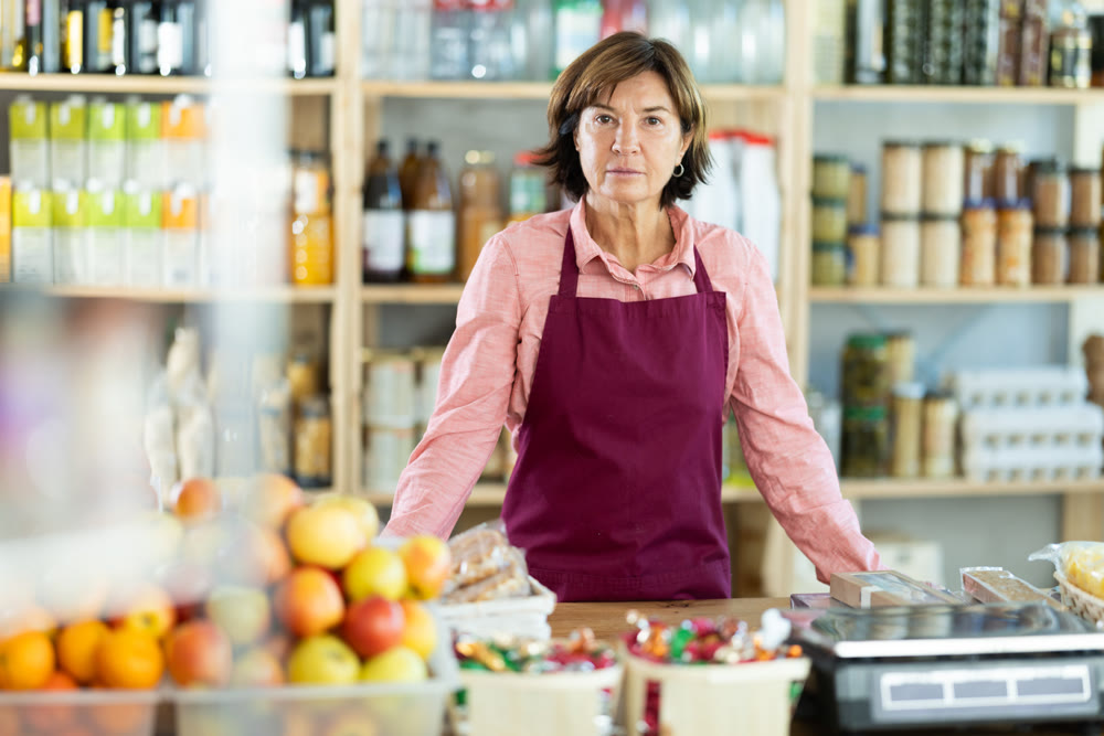 Mature saleswoman standing at the counter in grocery store