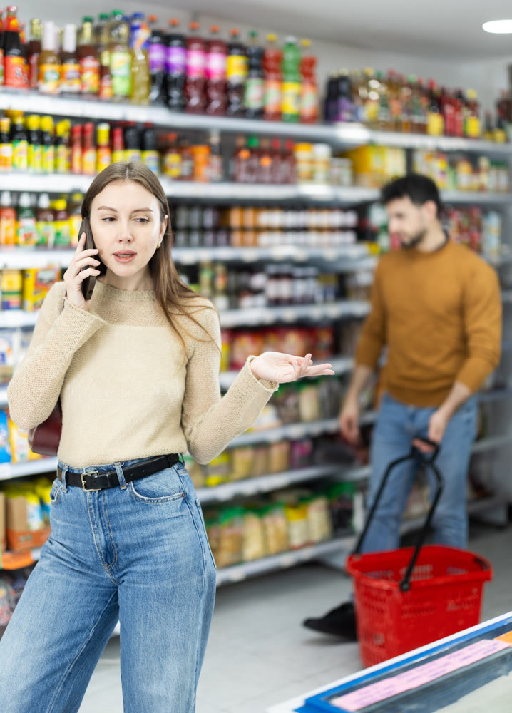 Young woman choosing groceries while talking on phone