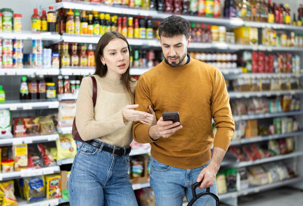 Young couple with mobile phone chooses products