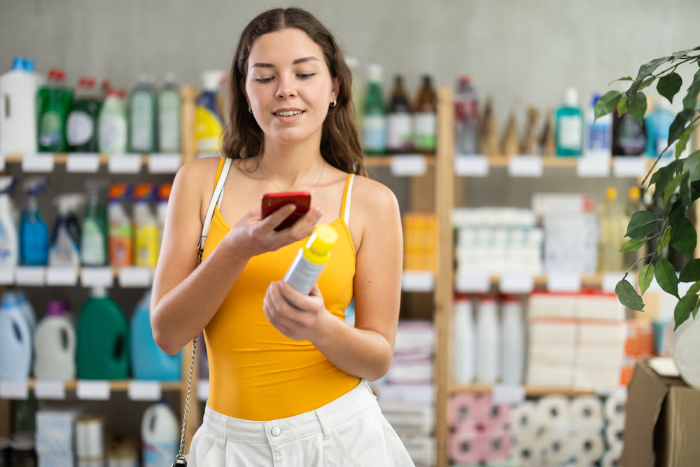 Checking expiration date of insect repellent - female shopper scans QR code on label of insect repellentusing smartphone