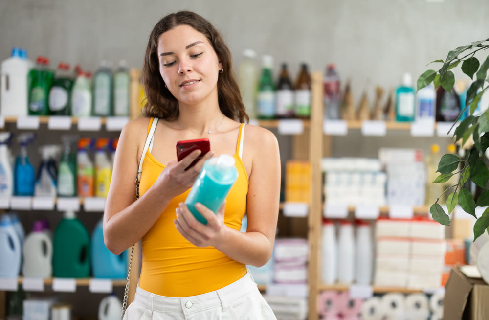 Girl scanning QR code on shampoo for online payment in store