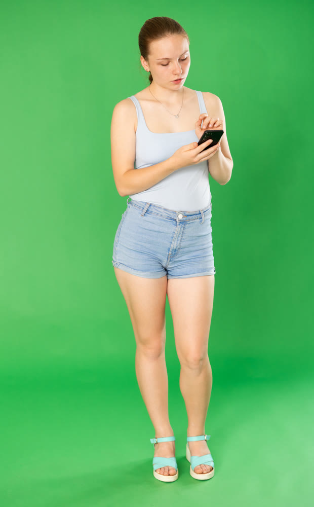 Teenage girl in blue top looks at information on smartphone screen. Chroma key compositing