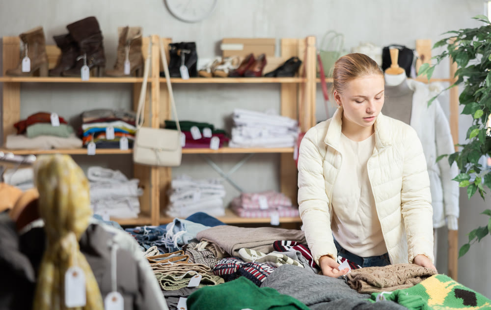 Selective teen girl choosing sweater in clothing store
