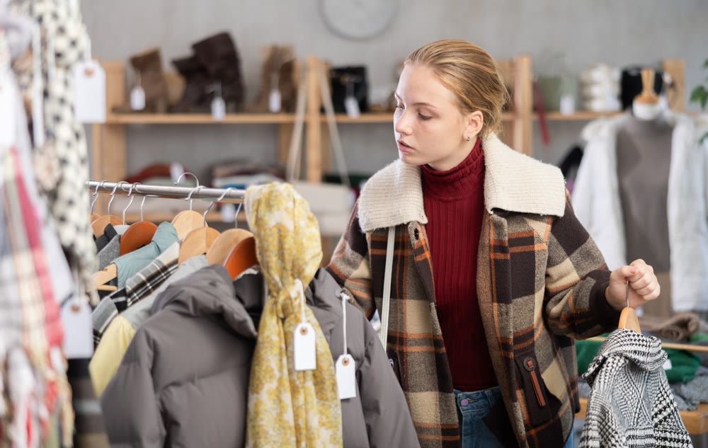 Attentive teenage girl choosing something for autumn-winter in clothing store