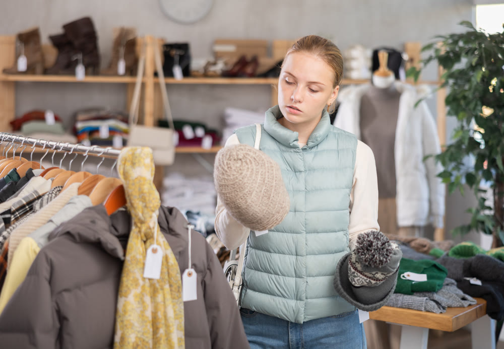 While shopping, girl browsing goods items and choose elect warm hat in store
