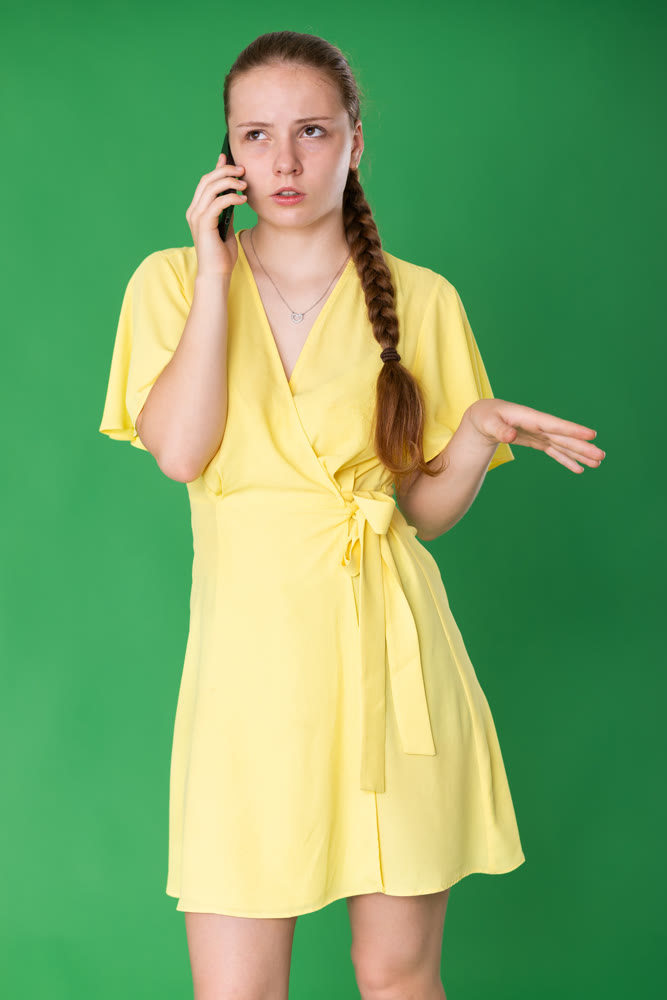 Teenage girl talking on mobile phone on green background.