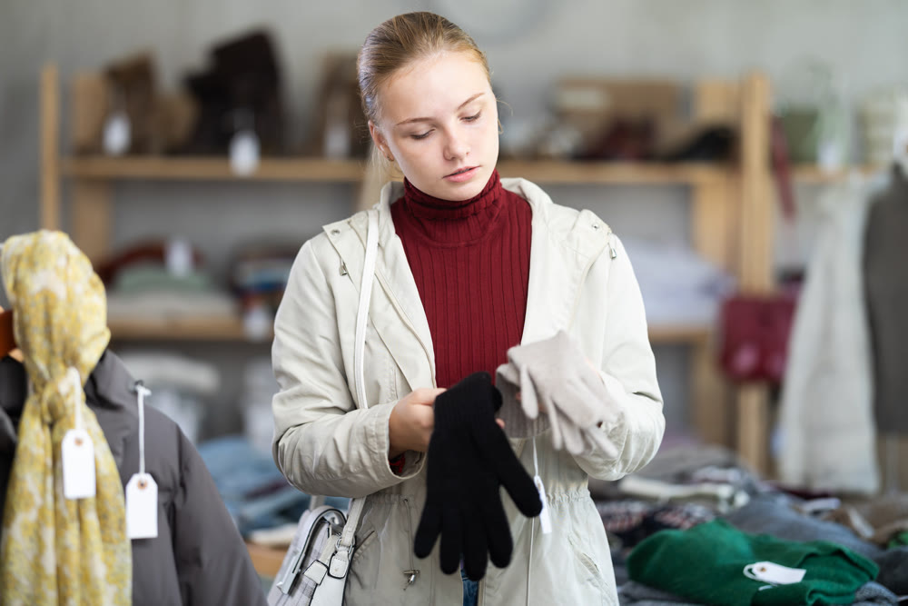 While shopping, teen girl browsing goods items and choose elect warm gloves in store