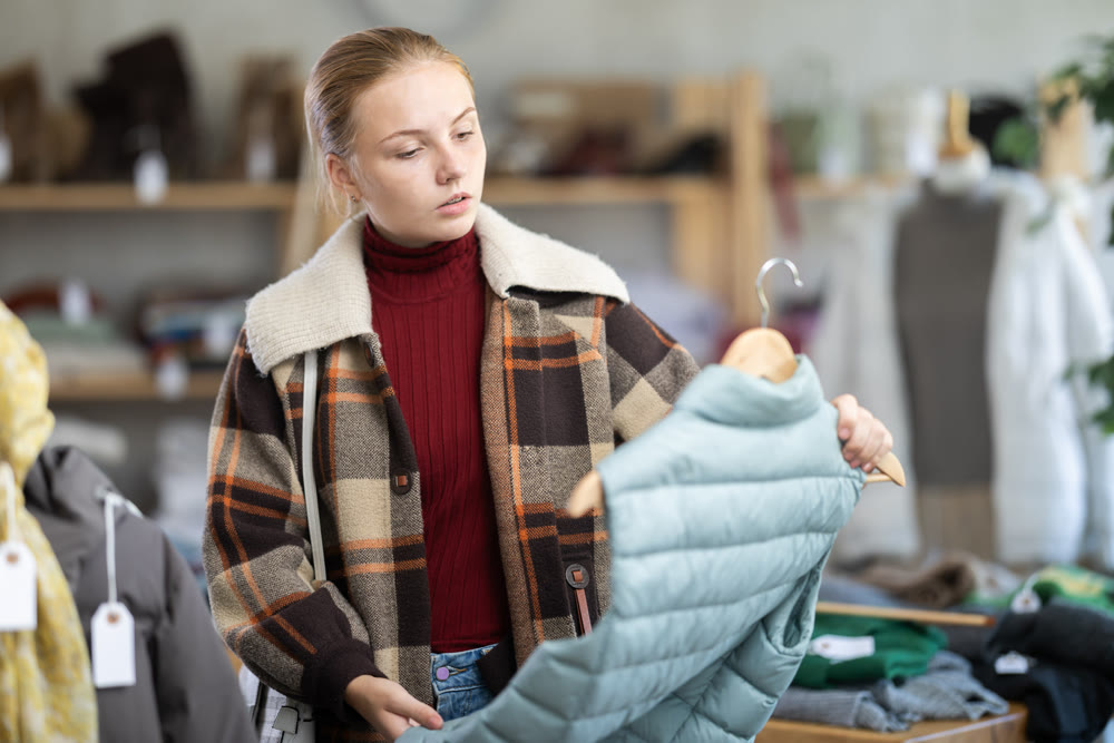 While shopping, teen girl browsing goods items and choose elect down vest in store