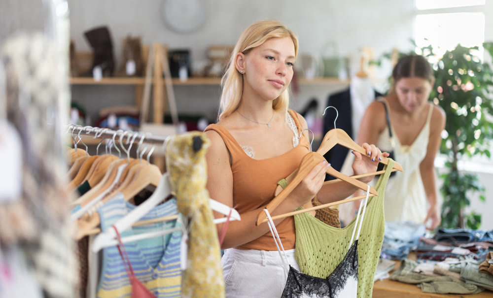 Young woman with her friend choosing top in store