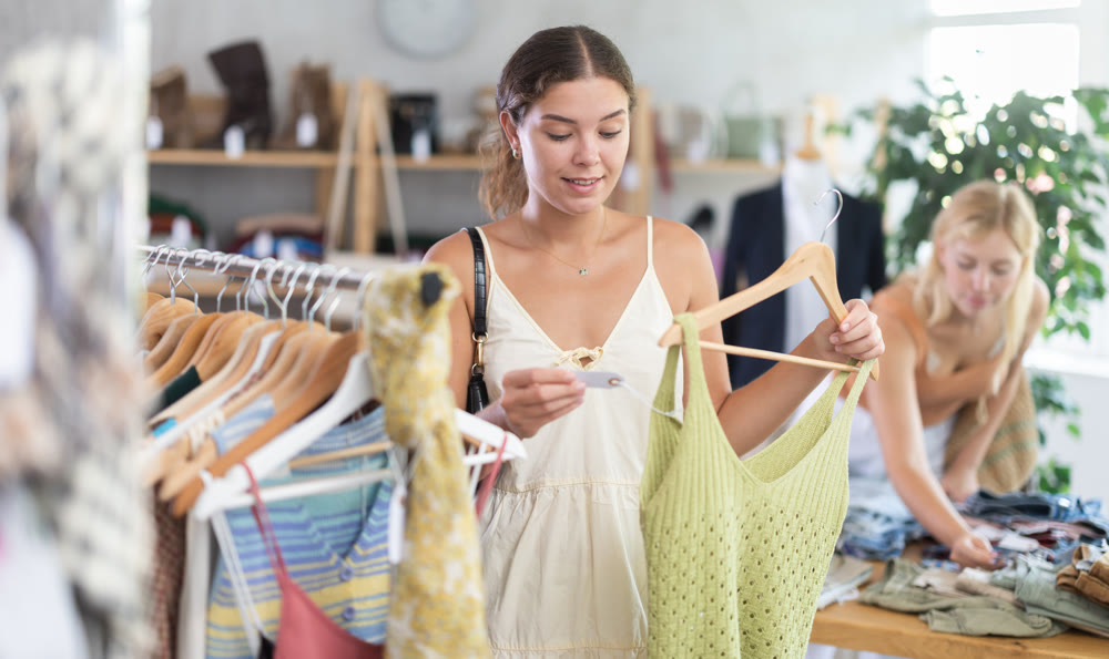 Girl buying something clothing for summer. Female client looking for something in background