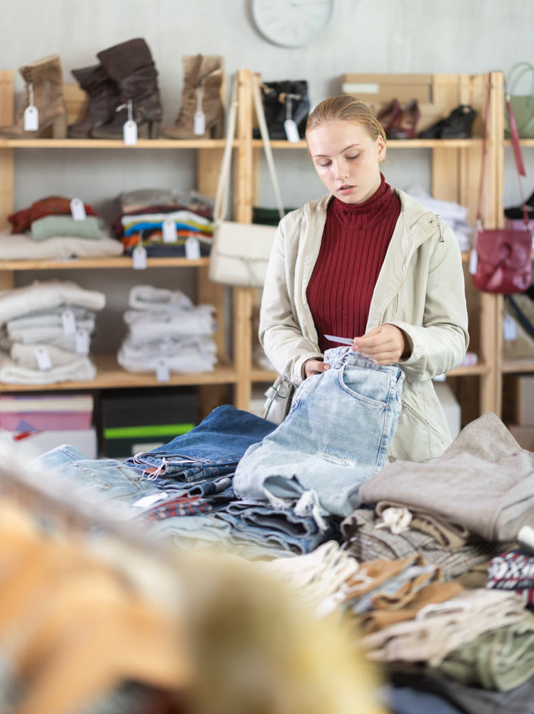 Selective teen girl choosing jean pantaloons in clothing store
