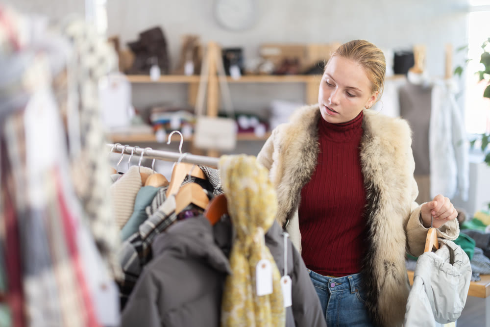 Attentive teenage girl choosing something for autumn-winter in clothing store