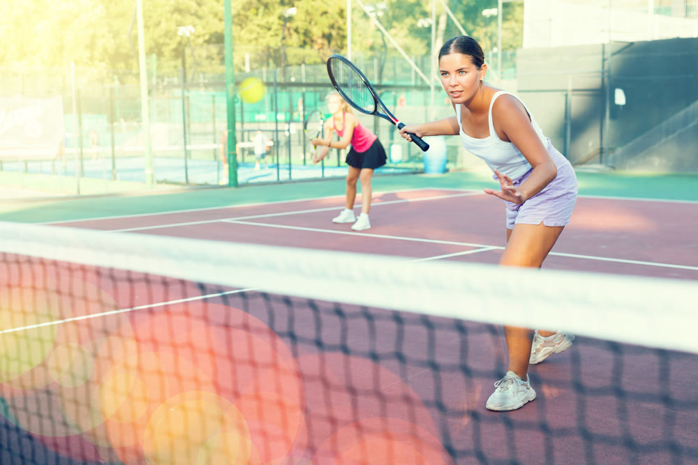 Portrait of concentrated energetic girl playing tennis, preparing to hit forehand to return ball close to net