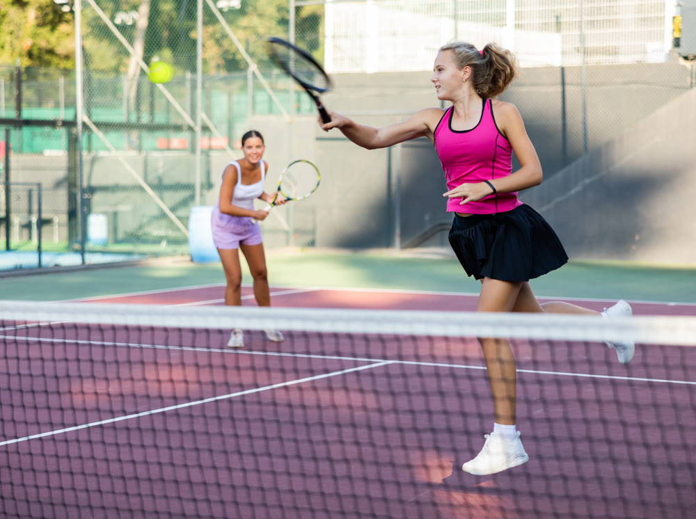 Active young tennis girl dressed in pink t-shirt and skirt on court ready for playing and training