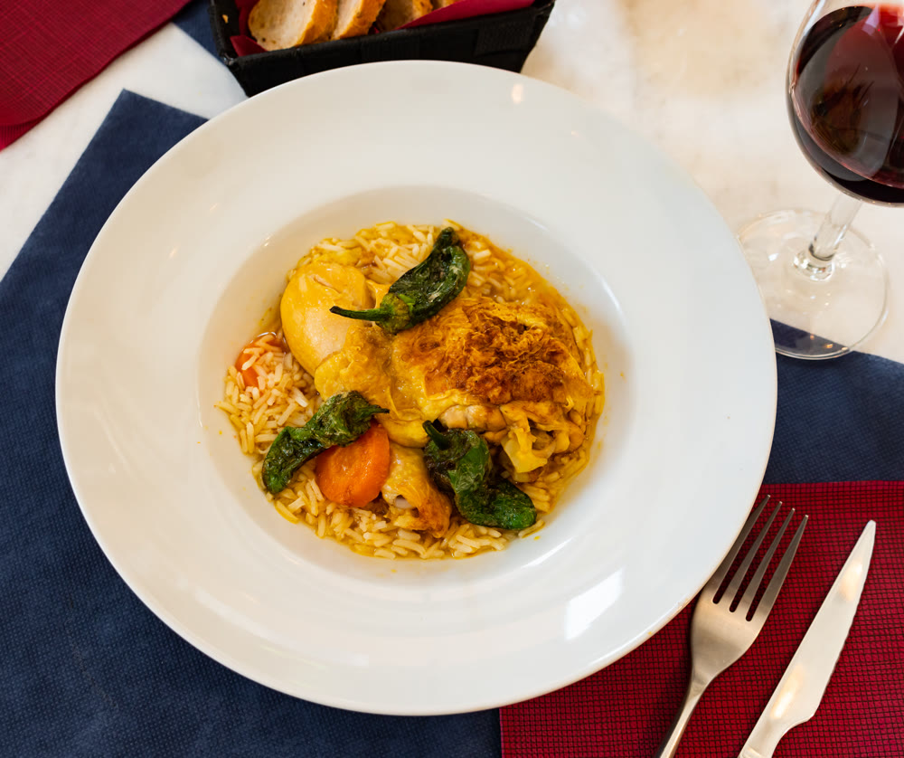 Dish of chicken thigh curry with rice and padron pepper
