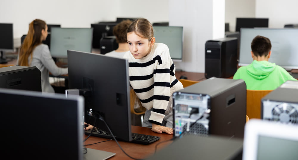 Young girl learning to use personal computer during lesson