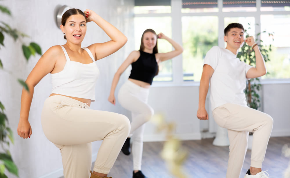Cheerful young girl enjoying active dancing during group training