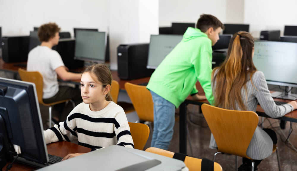 Young girl learning to use personal computer during lesson
