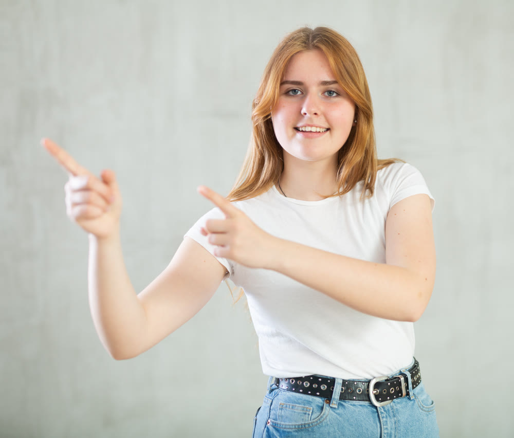Excited girl holding palm open for new product or sale presentation.