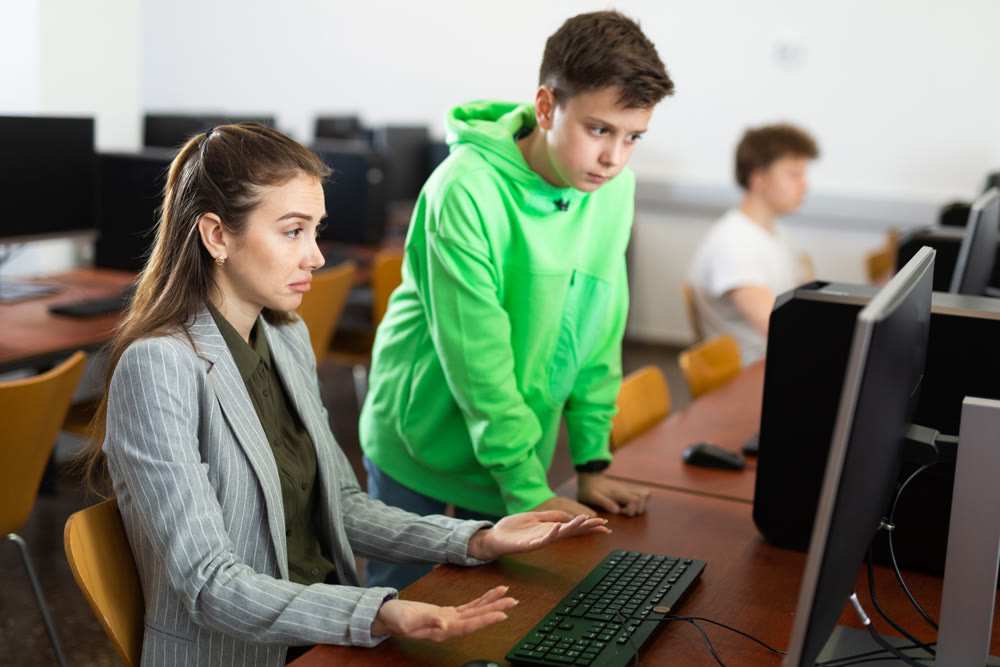 Teacher and pupil trying to solve computer problem