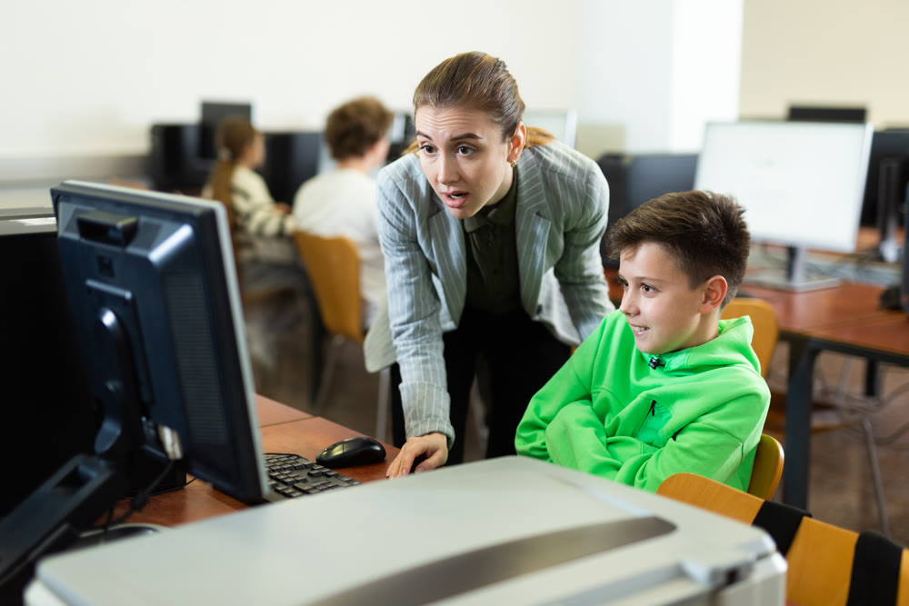 Teacher together with students conduct lesson on computer education