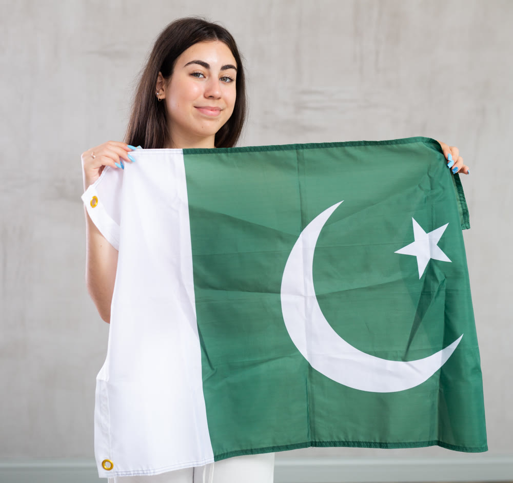 Young woman with flag of Pakistan posing in studio