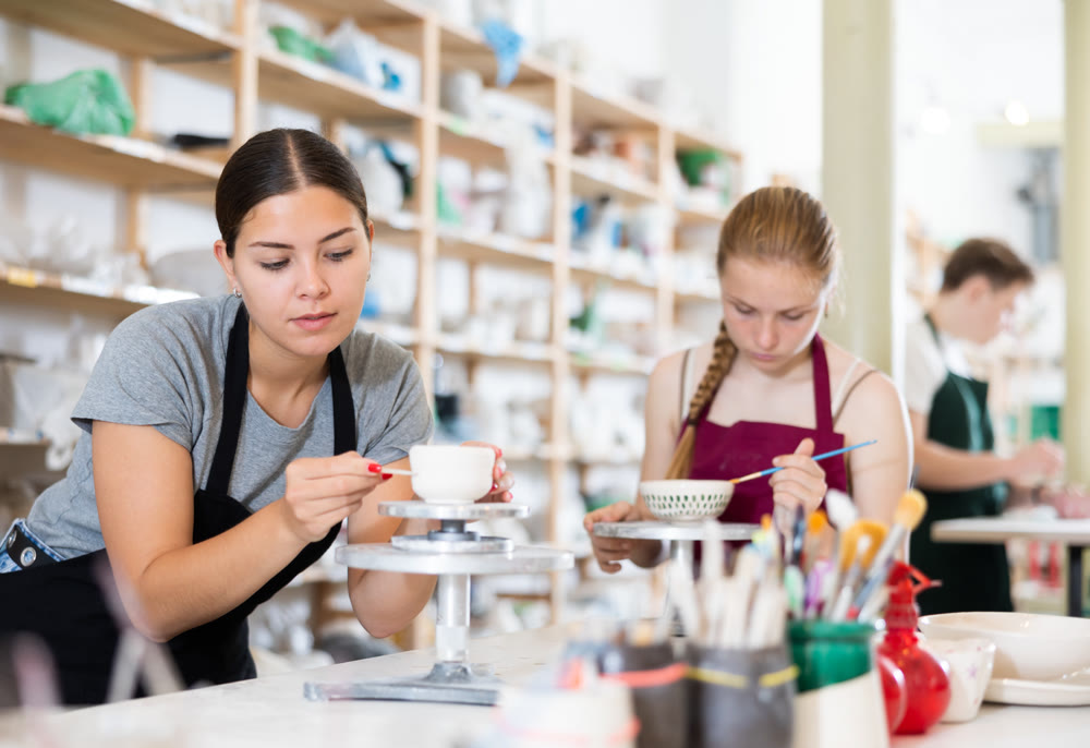 Young woman teacher making ceramic cup