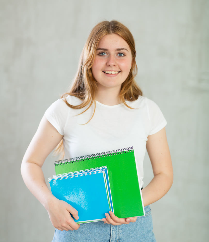 Young happy girl student hold books on gray background studio portrait. Education in high school university college concept