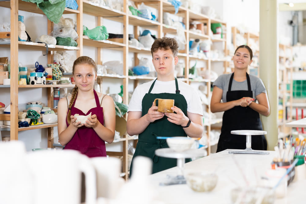 Teen boy and teen girl posing with ceramics