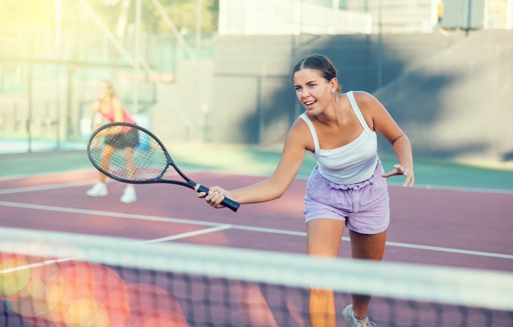 Portrait of concentrated energetic girl playing tennis, preparing to hit forehand to return ball close to net