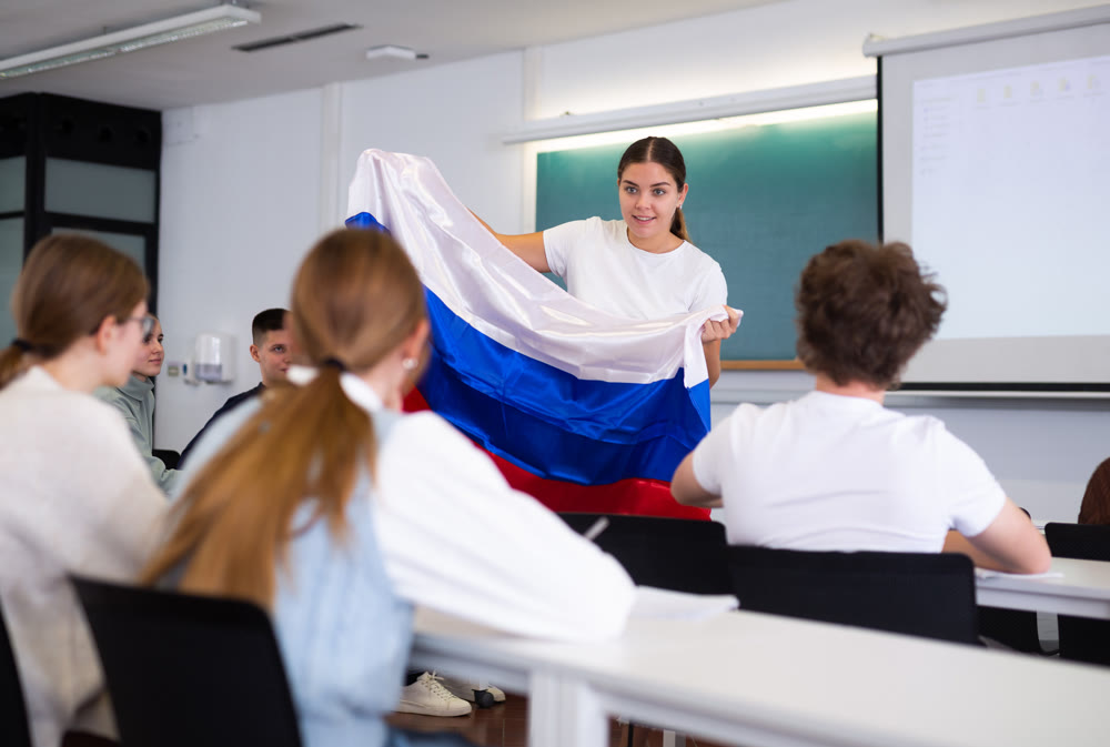 Adult female teacher showing Russian flag to students