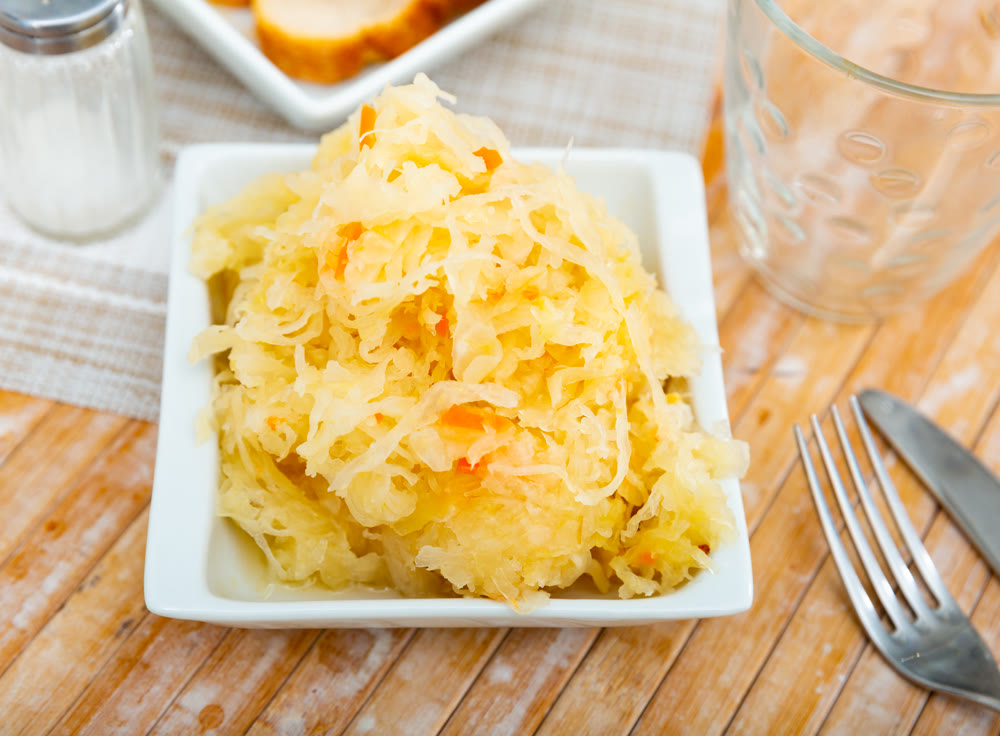 Homemade pickled cabbage on white plate closeup, natural probiotic